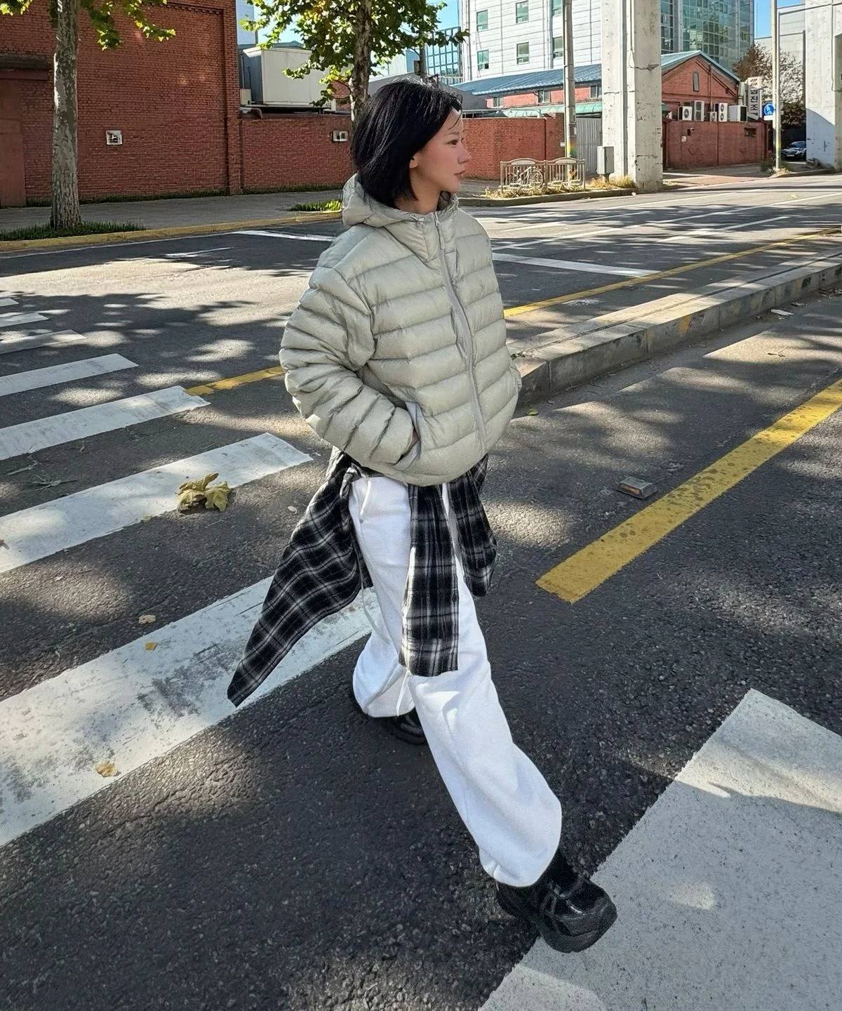 165cm 화자가 재킷을 입고 야외 공원에서 밑단 스트링을 조절하며 활동적인 포즈를 취하는 장면
